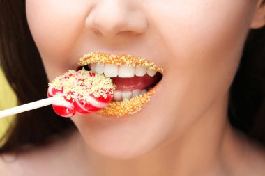 Yaratıcı makyajı ve lolipopu olan genç ve güzel bir kadının dudakları.