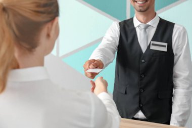 Erkek resepsiyonist otel odasından müşteriye anahtar kartı veriyor.