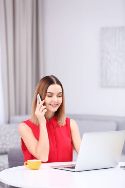 İçerideki masada cep telefonu kullanan genç bir kadın.