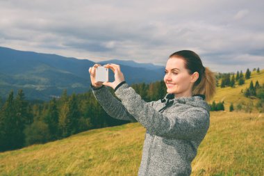 Güzel dağ manzarasının fotoğrafını çeken dişi turist.