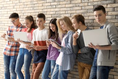 Tuğla duvarının yakınında modern cihazlar ile serin genç grup