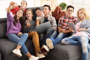 Genç modern cihazlar kapalı kanepede otururken selfie alarak ile grup