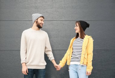 Gri duvarın yanında poz veren son moda hippi çift.