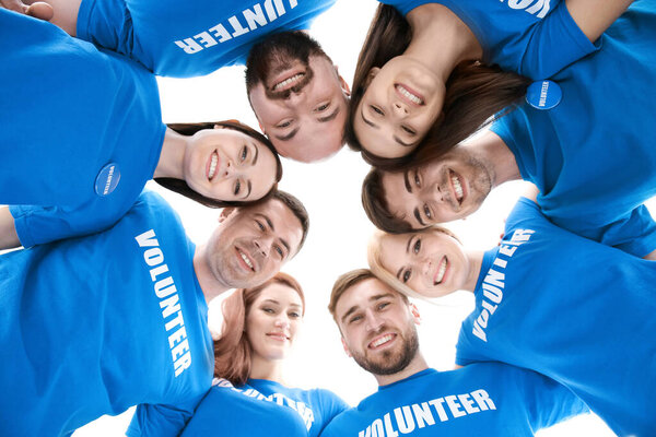 Молодые волонтеры с головами вместе в кругу на белом фоне
