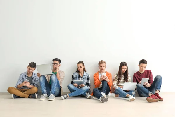 Groep Tieners Met Moderne Apparaten Zitten Vloer Buurt Van Muur — Stockfoto