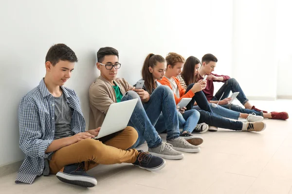 Група Підлітків Сучасними Пристроями Сидять Підлозі Біля Стіни — стокове фото