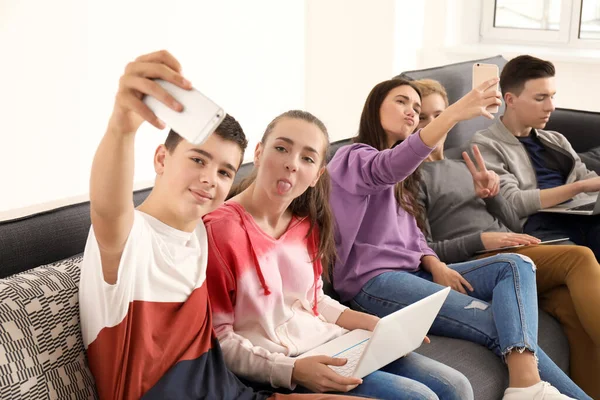 Grupo Adolescentes Com Dispositivos Modernos Tomando Selfie Enquanto Senta Sofá — Fotografia de Stock