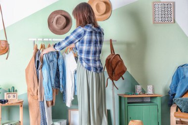 Kadın soyunma odasında elbise seçiyor.