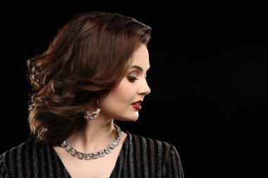 Koyu arkaplanda zarif mücevherleri olan güzel bir kadın.