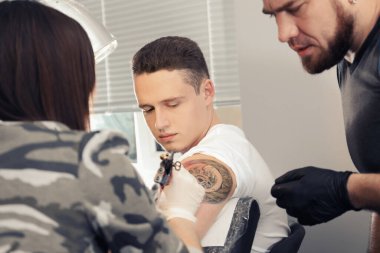 Profesyonel dövme ustası, kuaförde genç bir uzmana ders veriyor. Staj konsepti