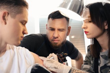 Profesyonel dövme ustası, kuaförde genç bir uzmana ders veriyor. Staj konsepti