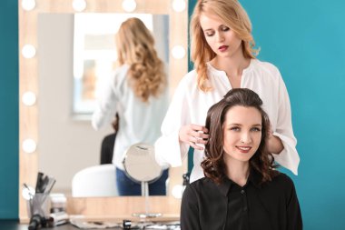 Profesyonel kuaför müşteriyle kuaförde çalışıyor.