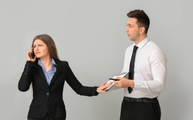 Erkek sekreter ve yoğun patronu arka planda.