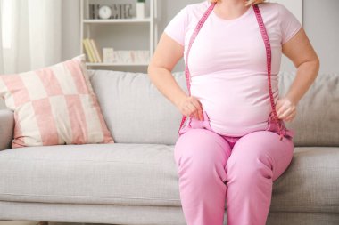 Dar elbiseli, kilolu bir kadın ve evde mezurası var.