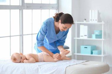 Tıp merkezinde şirin bir bebekle çalışan masaj terapisti.