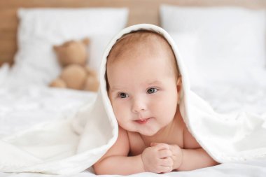 Evde yatağında havluyla yatan tatlı bir bebek.