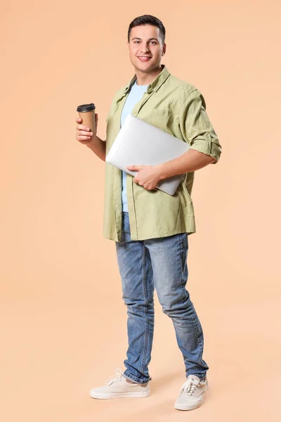 色の背景にラップトップとコーヒーと若い男の肖像画 — ストック写真