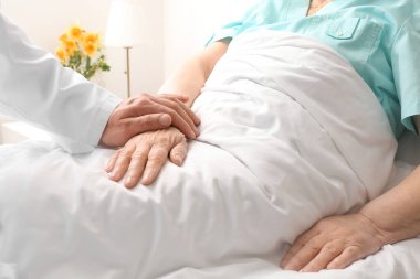 Hasta odasında yaşlı bir hastayla erkek doktor.