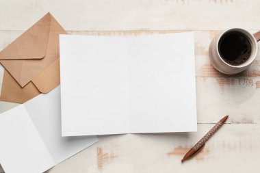 Açık ahşap zemin üzerinde boş kartlar, zarf ve kahve olan kompozisyon