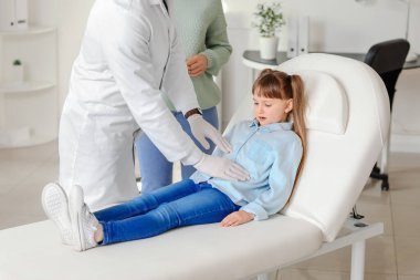Gastroenterolog klinikteki küçük kızı muayene ediyor.