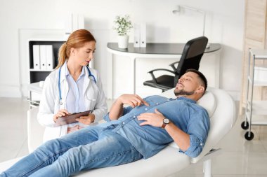 Gastroenterolog klinikteki adamı inceliyor.