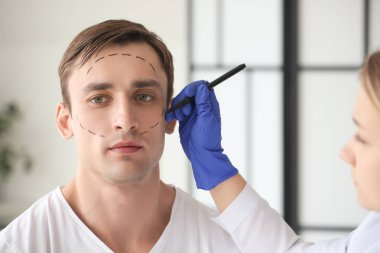 Plastik cerrah klinikte adamın yüzüne izler yapıştırıyor.