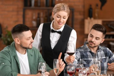 İnsanlar restoranda şarap tadıyor.