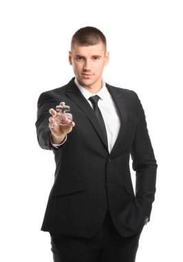 Beyaz arka planda parfüm şişesi olan yakışıklı bir genç.