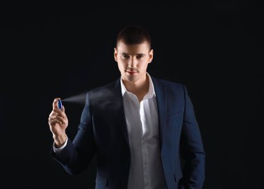 Esmer arka planda parfüm şişesi olan yakışıklı bir genç.