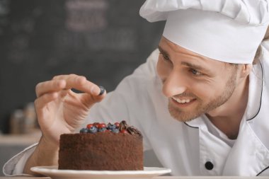 Erkek şekerci mutfakta lezzetli bir tatlı hazırlıyor.