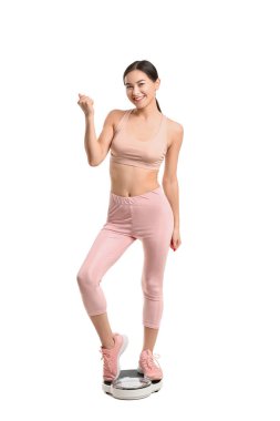 Beyaz arka planda ağırlığını ölçen genç bir kadın.