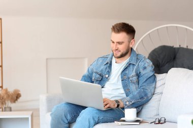 Bilgisayarlı genç adam evde çalışıyor.