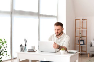 Bilgisayarlı genç adam evde çalışıyor.