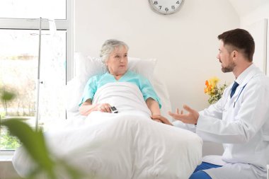 Hasta odasında yaşlı bir hastayla çalışan erkek doktor.