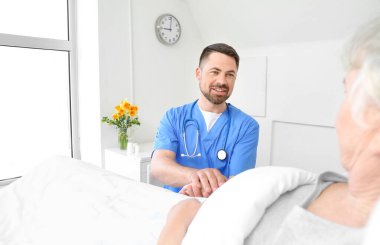 Hasta odasında yaşlı bir hastayla çalışan erkek doktor.