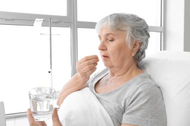 Hastane odasında ilaç alan yaşlı bir kadın.