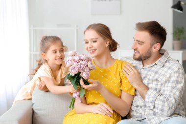 Küçük kız annesi için bir buket çiçek veriyor.