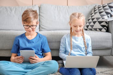 Evde dizüstü bilgisayarı ve tableti olan şirin çocuklar. Çevrimiçi eğitim kavramı