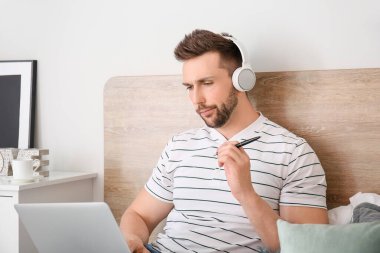 Bilgisayarlı genç adam evde çalışıyor.