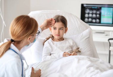 Hastane odasında küçük bir kızla çalışan kadın doktor.