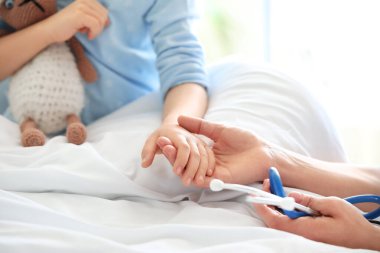 Hastane odasında küçük bir kızla çalışan kadın doktor, yakın plan.