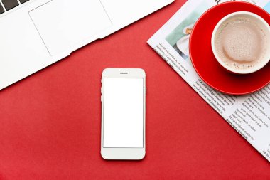 Dizüstü bilgisayarlı modern cep telefonu, bir fincan kahve ve arka planda gazete