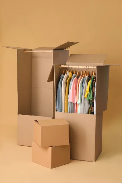 Moving boxes with clothes on color background