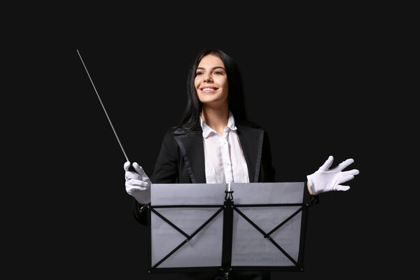Young female conductor on dark background
