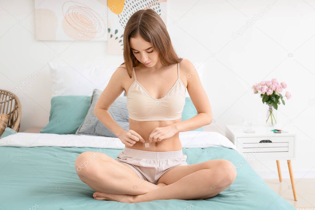 Young woman with contraceptive patch in bedroom