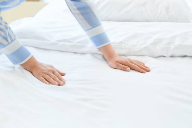 Kadın evde yatak yapıyor.