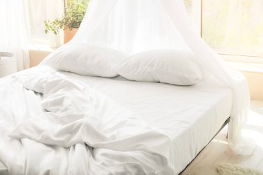 Odasında temiz çarşaf olan büyük, rahat bir yatak.