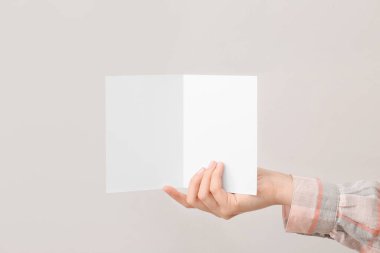 Açık arkaplanda boş kartı olan bir kadın el.