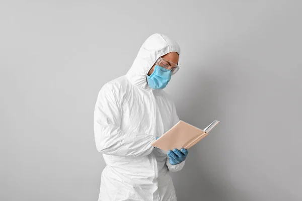 Man Biohazard Suit Reading Book Grey Background — Stock Photo, Image