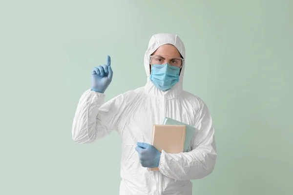 Man Biohazard Suit Books Raised Index Finger Color Background — Stock Photo, Image